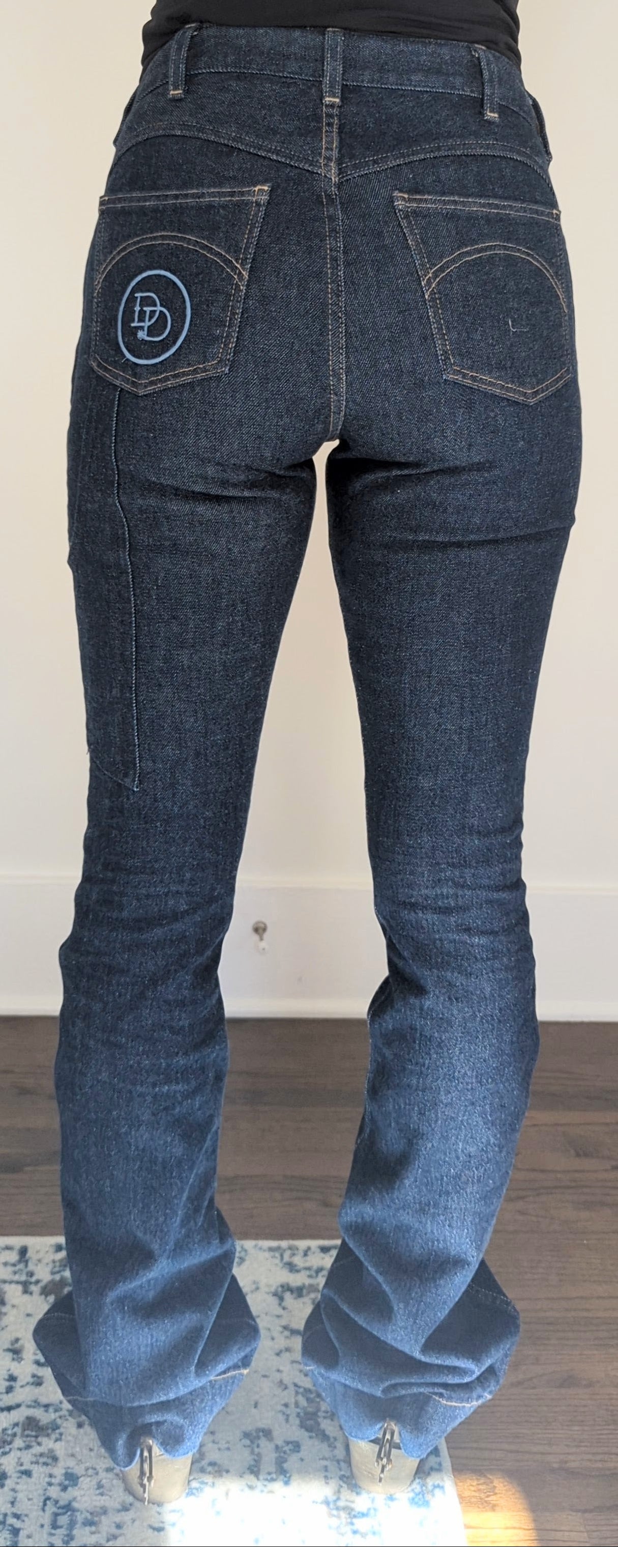 Blue jeans with a brand logo on the back pocket against a neutral background